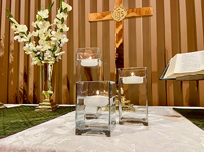 Three floating candles with cross and flowers on the altar