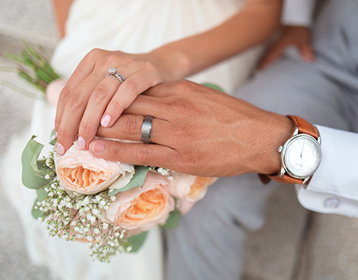 bride and groom holding hands with rings and flowers